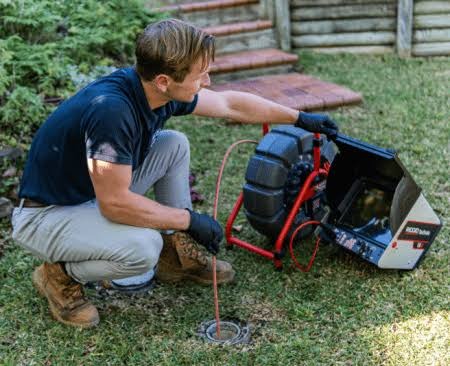 Houston drain technician operating high-definition sewer camera inspection monitor and push reel in Houston, TX 77002